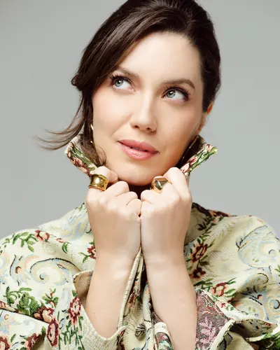 A atriz Nathalia Dill agachada, com conjunto estampado de flores, em fundo cinza, para a Marie Claire Brasil